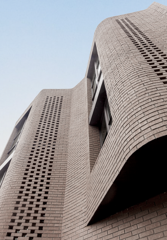 Perforated brickwork curving upward against the sky