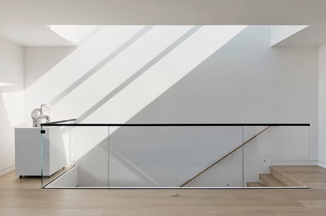 Upper landing with glass balustrade and skylight shadows