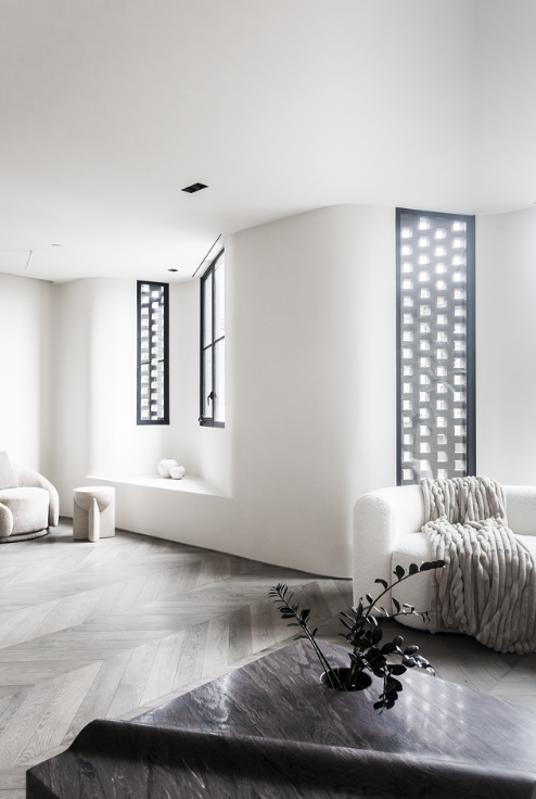Bright interior with curved wall, patterned windows and herringbone floors
