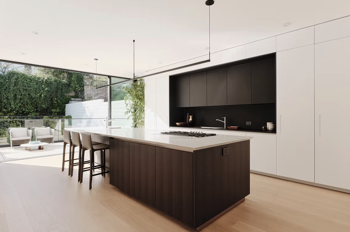 Kitchen with dark timber island and full-height glazing to the terrace