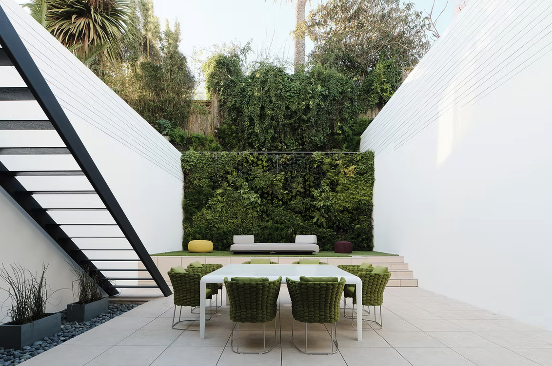 Walled courtyard with dining table and living green wall